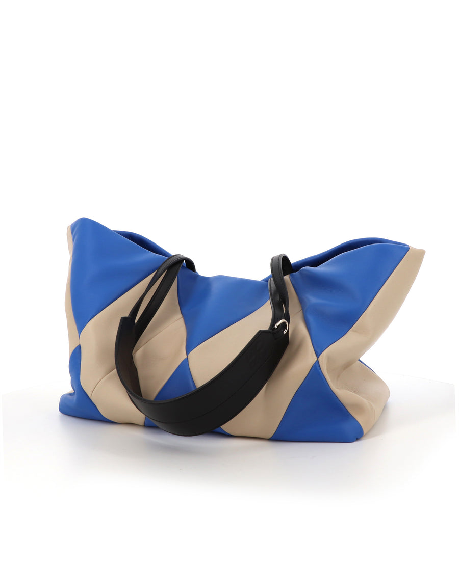RECO Paris TRIXI bag in electric blue and white worn by a woman as a large tote for travel or work.